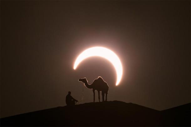 Annular solar eclipse in desert with a silhouette of a dromedary camel. Liwa desert, Abu Dhabi, United Arab Emirates. (Kertu / Adobe Stock)