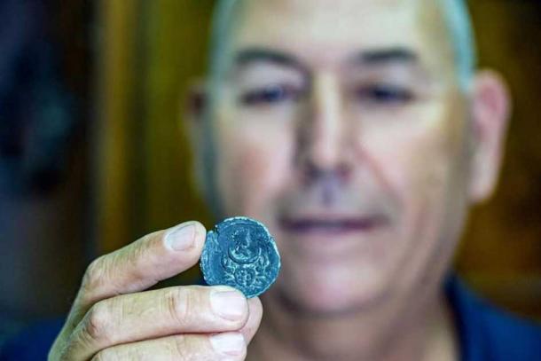 Israel Antiquities Authority Maritime Archaeology Unit Director Jacob Sharvit holding the rare bronze Roman coin. (Yaniv Berman / Israel Antiquities Authority)