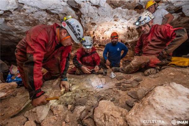 Arqueólogos del Instituto Nacional de Antropología e Historia (INAH) observan fragmentos de cerámica en una cueva, como parte del trabajo arqueológico que acompaña la construcción de un polémico nuevo tren. (Oficina Península de Yucatán del SAS-INAH)