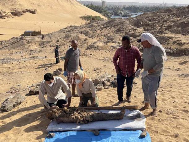 Los arqueólogos de la Misión Italo-Egyptian examinan una momia recién excavada en el sitio de entierro grecorromano en el oeste de Asuán. (Misión Egipcio-Italiana (EIMAWA))