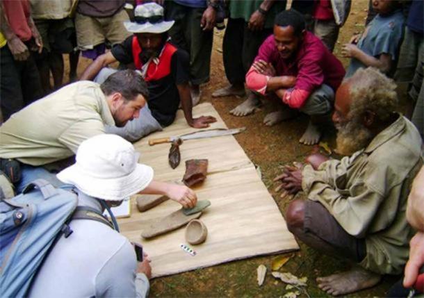Dr Ben Shaw and some locals examine a few of the Papua New Guinea artifacts unearthed at the Waim dig site. ( UNSW / Ben Shaw)