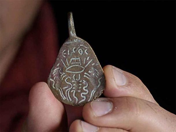El reverso del amuleto bizantino de bronce muestra un ojo atravesado por flechas y una horca. (Dafna Gazit/Autoridad de Antigüedades de Israel)