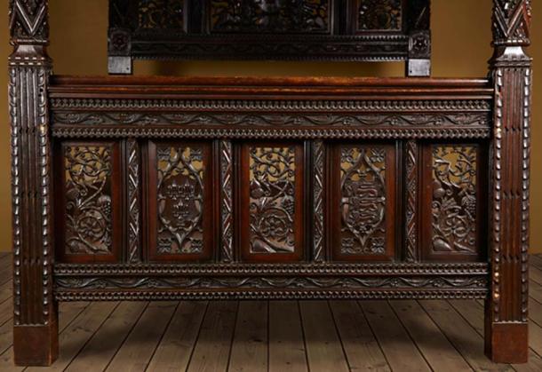 Carved portraits on the foot board of the antique bed. (The Langley Collection)