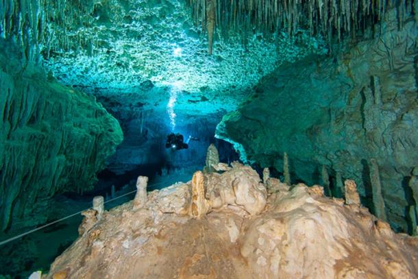 Cave diver hovering in one of the grand decorated hallways of the cave system from Cenote Chan Hol in Mexico