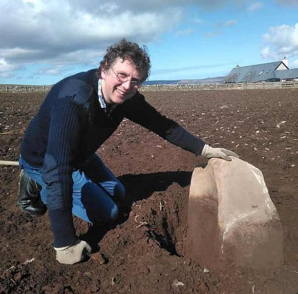 Chris Gee, from the Orkney Research Centre for Archaeology (ORCA), with the massive saddle quern revealed by ploughing earlier this month. (Ragnhild Ljosland / Archaeology Orkney)