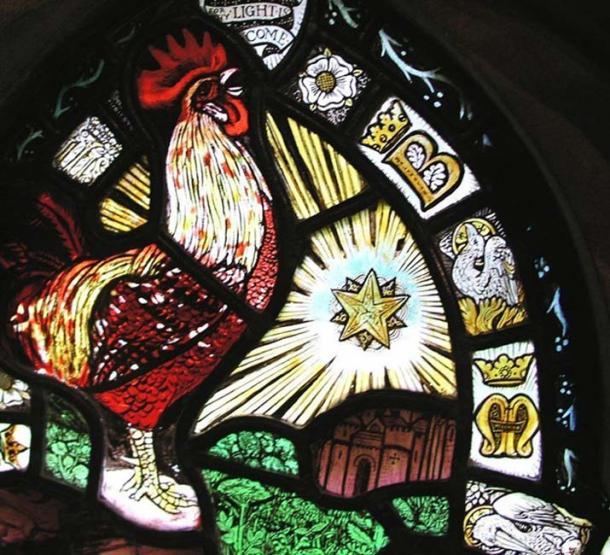 Close up of the Epiphany Window, showing the double star, the rooster, the phoenix, and the letters B and M. The red-brick arch can be seen directly below the star.