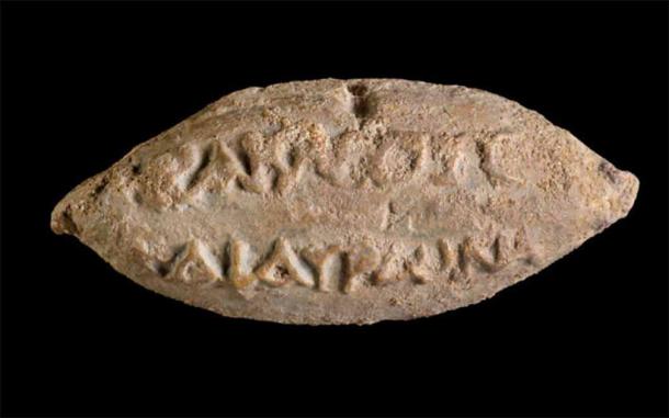 Los nombres de los dioses Heracles y Hauron en el reverso de una bola de honda encontrada en Yavne. (Dafna Gazit/Autoridad de Antigüedades de Israel)