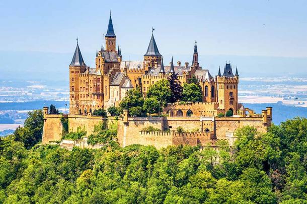 Zámok Hohenzollern v Nemecku bol kedysi domovom šľachtických Hohenzollernov.  Neogotický hrad v štýle typického stredovekého hradu na kopci sa pohodlne nachádza na vrchole hory Berg Hohenzollern s výškou 855 metrov.  V súčasnosti je obľúbenou turistickou destináciou vďaka nádhernej architektúre 140-izbovej rozprávkovej pevnosti.  (scaliger/Adobe Stock)