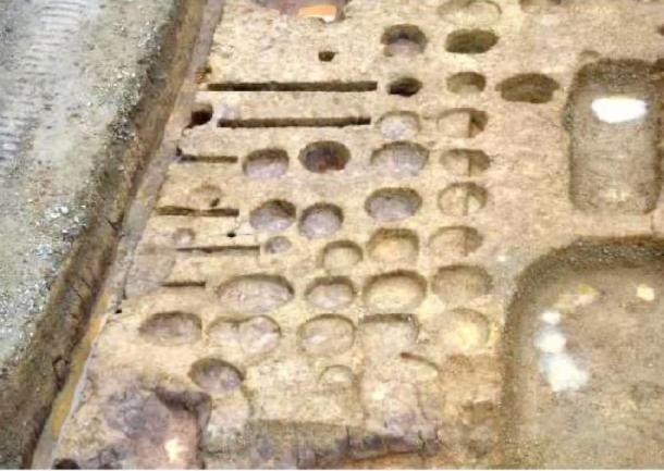 Holes for holding storage jars unearthed at the sake brewery in Kyoto, Japan. (Kokusai Bunkazai Co.)
