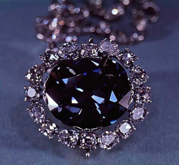 El diamante Hope, uno de los más grandes de todos los diamantes azules, 45,52 quilates, en exhibición en el Museo Nacional de Historia Natural. La joya está ligeramente desequilibrada, posiblemente porque la parte inferior de la forma de lágrima se ha cortado para que no se pueda identificar la joya robada original. El engaste es un círculo de pequeños diamantes blancos en una cadena de diamantes. (Dominio publico)