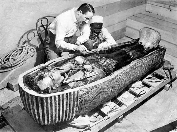 Howard Carter and an Egyptian workman examine the third (innermost) coffin of Tutankhamun made of solid gold, inside the case of the second coffin. (Public Domain)