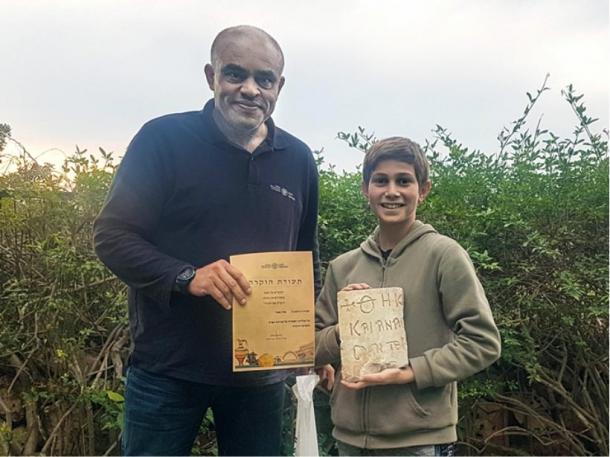 Karem Said, Haifa district archaeologist at the IAA, awards Stav Meir with a certificate of appreciation for his find of the 1,500-year-old Byzantine inscription near Caesarea. (Karem Said/ Israel Antiquities Authority)