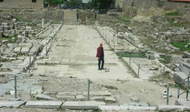 Lechaion Road, entering from the north-west (top) and facing south-east, with Acrocorinth in the background (bottom).