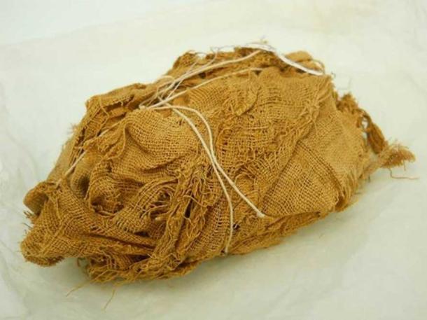 Linen bundle still wrapped (supported by modern string) found in a rock cut tomb at Qau el-Kebir, c.1922-24. (Bolton County Council/Bolton Museum)