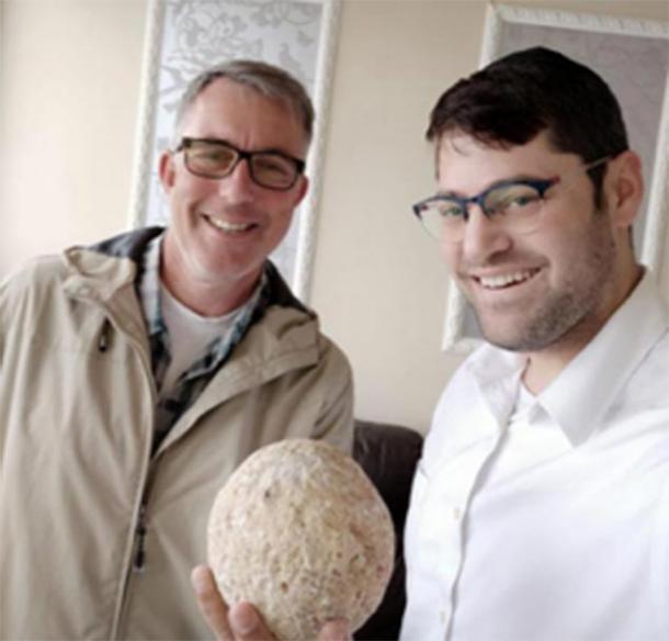 Moshe Manies (right) and Uzi Rotstein (left) of the Israel Antiquities Authority with the stolen ballista stone. (Moshe Manies / IAA)