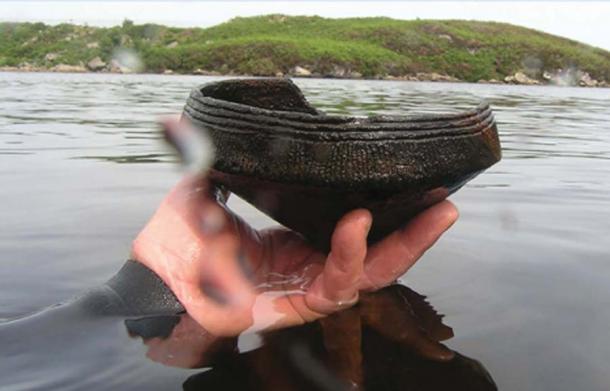 A diver holds a Neolithic ca. 3,500 BC Ustan vessel found near an underwater crannog in Loch Arnish, Scotland. (C Murray / Antiquity)