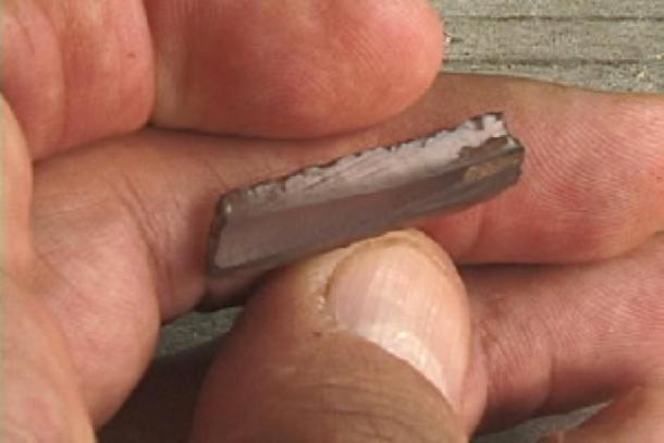 Obsidian prismatic blade fragment from the ancient Maya site of Chunchucmil, Yucatan. A prismatic blade is a long, narrow, specialized stone flake tool with a sharp edge, like a small razor blade. (David R. Hixson / CC BY-SA 2.5)