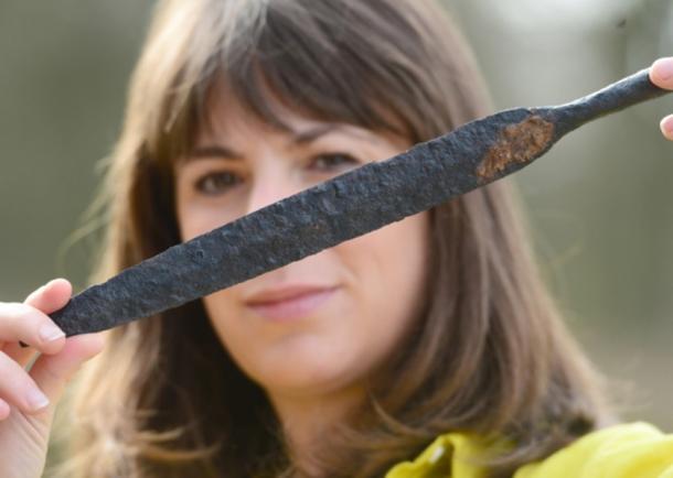 Map Archaeological Practice Ltd staff member Sophie Coy holds a spear head that was found at the site