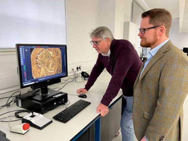 Professor Paul N. Pearson and Jesper Ericsson look at the Sponsian coin under a microscope. (The Hunterian / University of Glasgow)