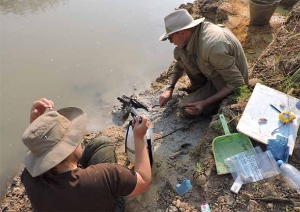 Professor Larry Barham (pictured, right) uncovering the wooden structure on the banks of the river with a fine spray. (Professor Geoff Duller, Aberystwyth University/Nature)