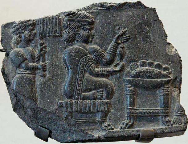 Relief of a woman being fanned by an attendant while she holds what may be a spinning device before a table with a bowl containing a whole fish. Circa 700 - 550 BC, Susa. Representational image.