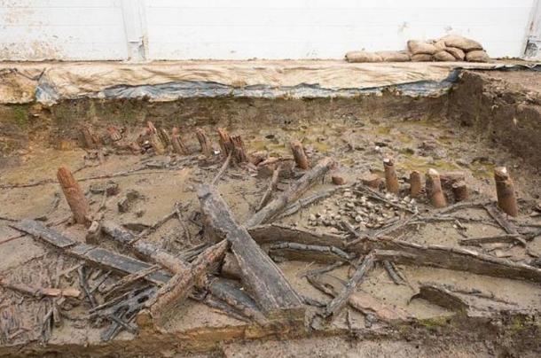 Remains of a house at Must Farm showing the unburnt stumps of posts under the waterline during the fire (top-right) and collapsed joists