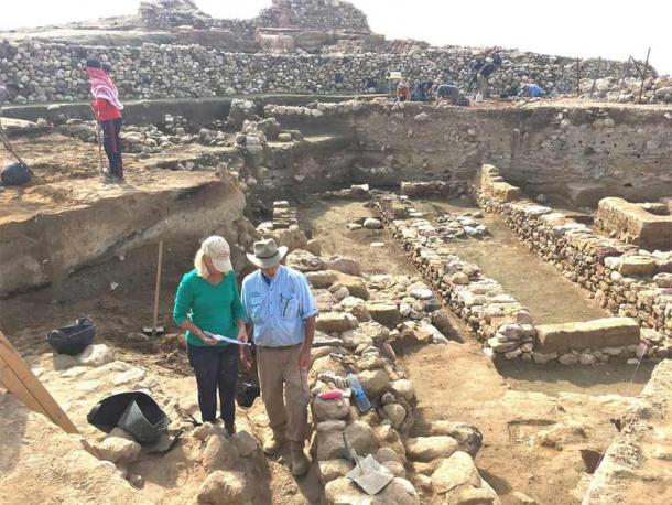 Researchers stand near the ruins of ancient walls, with the destruction layer about midway down each exposed wall. (Phil Silvia /Scientific Reports))