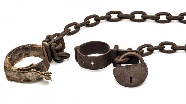 Rusty old shackles with padlock and padded shackles used for locking up prisoners or slaves between 1600 and 1800 during the slave trade, which is not so different from how Roman slaves in Britannia were treated. In fact, many Roman slaves all over the Empire were treated horribly and not properly buried. (Asmus Koefoed / Adobe Stock)