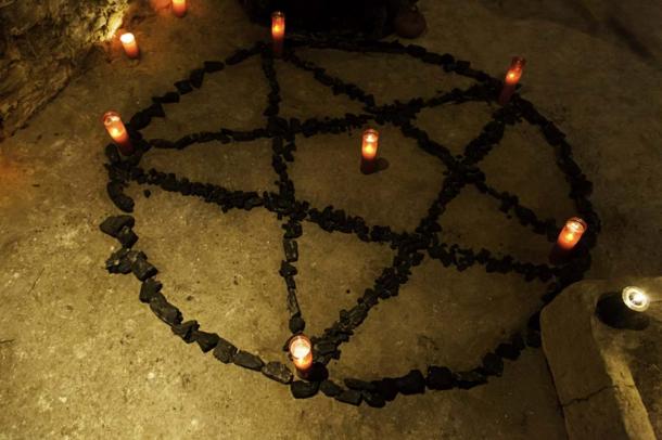 Satanic pentacle with candles in a dark ritual (esebene / Fotolia)