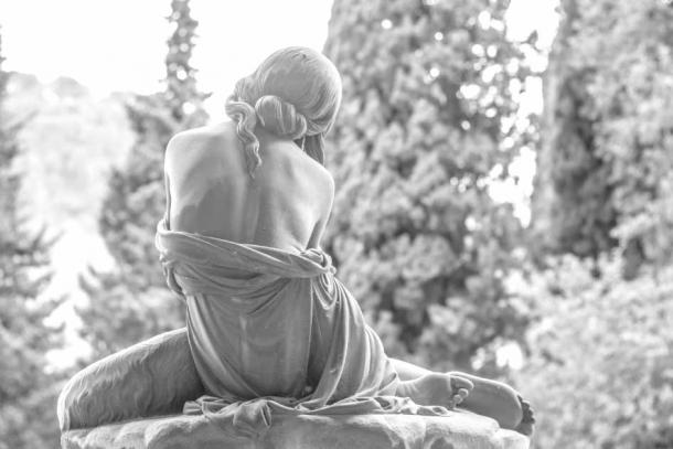 Sculpture of a woman sitting in silence and reflection on top of the tomb of a loved one. (RusskyMaverick / Adobe Stock)