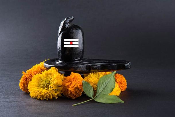 Shivalinga made up of black stone decorated with flowers & bael leaf known as Aegle marmelos (StockImageFactory / Adobe Stock)