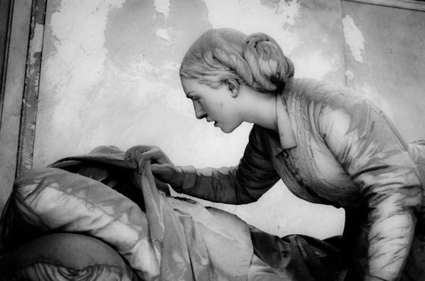 Statue of a woman peering below a shroud covering a deceased loved one. Staglieno Cemetery, 1881 (Andrea Vismara / Adobe Stock)