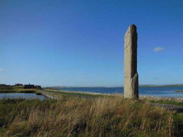 The 5.6 meter tall Watchstone on the Orkney Mainland and behind it the isthmus dividing Loch Stenness (left) and Loch Harray (right). This enormous stone pillar once formed part of an almighty avenue of stones. (Image: © Andrew Collins).