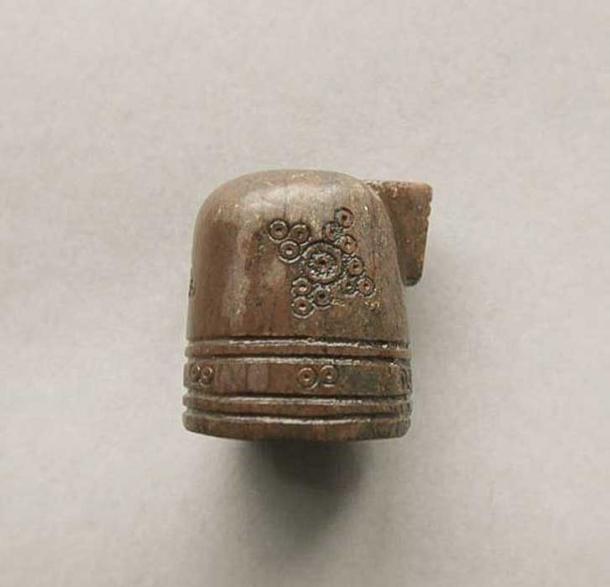 The piece is made from antler and is covered with circular designs.