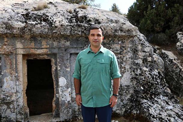 Turkish archaeologist Durmuş Altan standing in front of the blasted open Lycian rock-cut tomb. (Yenisafak)