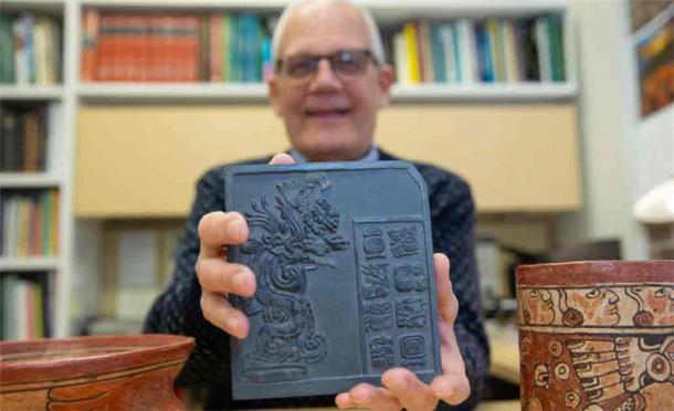 UC Professor David Lentz holds up a sculpture that bears reproductions of ancient Maya glyphs. (Andrew Higley/UC Marketing + Brand)