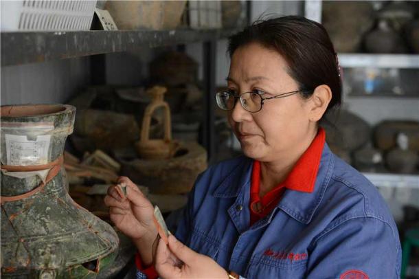 Xu Weihong trabajando en un jarrón encontrado en el sitio antiguo de Xianyang. (Zhang Xiping/Diario de China)