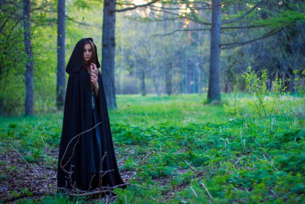 Wise Woman in black cloak in the forest