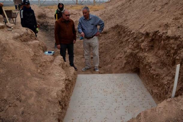 El Dr. Ali A. Yassin al-Jabouri y el representante Fadhel Mohamad examinan la puerta inscrita recientemente descubierta en el palacio del rey asirio Adad-Nerari (811–783 a. C.) en Nimrud. (Michael Danti)