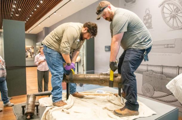Alamo Museum staff adjust the cannon in the display area.