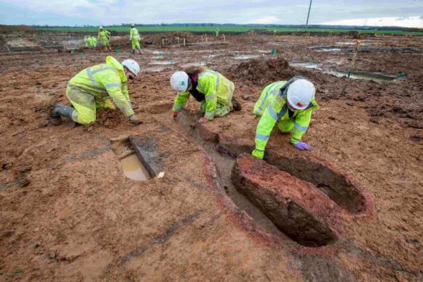 Three archaeologists excavating a Roman kiln at the site. The combustion chamber with its central pedestal is on the right. (MOLA)