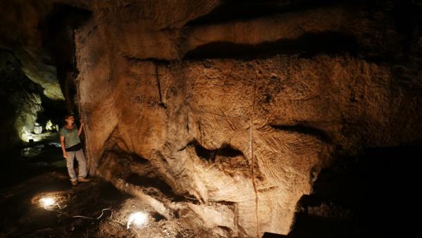 Ayala Amir in Israel's Te'omim Cave beside the wall of the quarry. Signs of quarrying-scars and cessation of quarrying are visible on the quarry’s walls and floor (Prof. Boaz Zissu, Bar-Ilan University/ Nature)