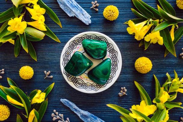 Malachite with blue kyanite and flowering yellow trumpet vine on blue stained wood. (Serena Tayyan / Adobe Stock)