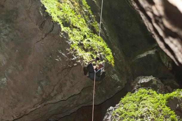 Chris rappelling down into the cave
