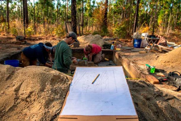 Archaeologists cleaning Continental burials. Excavation unit plan in foreground. (Sarah Nell Blackwell / South Carolina Battleground Trust)