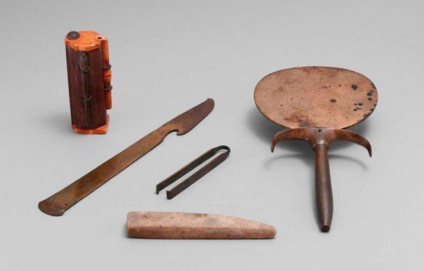This Egyptian cosmetics and toiletry set includes a tube for the eye cosmetic kohl, a razor, tweezers, a whetstone, and a mirror, circa 1550 BC. The objects were in a rush basket in a section of the Theban necropolis known as lower Asasif (Met Museum / Public Domain)