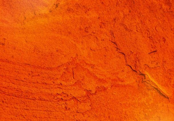 Una pared de color ocre rojo agrietada que los humanos antiguos en el norte de China tuvieron que romper en pedazos manejables para martillar y abrasar. (Buenas fotos/Adobe Stock)