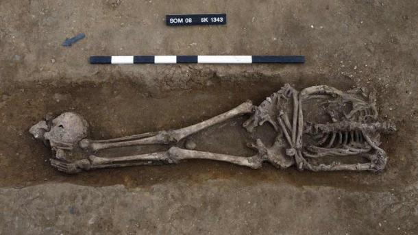 Un cráneo decapitado junto a los pies de la víctima en el cementerio romano en el Reino Unido. (Dave Webb / Unidad Arqueológica de Cambridge)