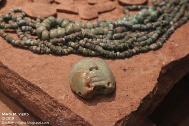 Parte de una ofrenda descubierta cerca de la cima de un montículo sin excavar en San Miguel Ixtapan durante trabajos eléctricos.  Incluye una máscara de piedra de mosaico, un collar de jade, aretes y un pequeño colgante en forma de cabeza humana con rasgos posiblemente olmecoides.  (Autor proporcionado)