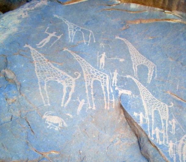 Giraffes and what look like a goat, a dog, people and cows on cave walls in the Egyptian Sahara